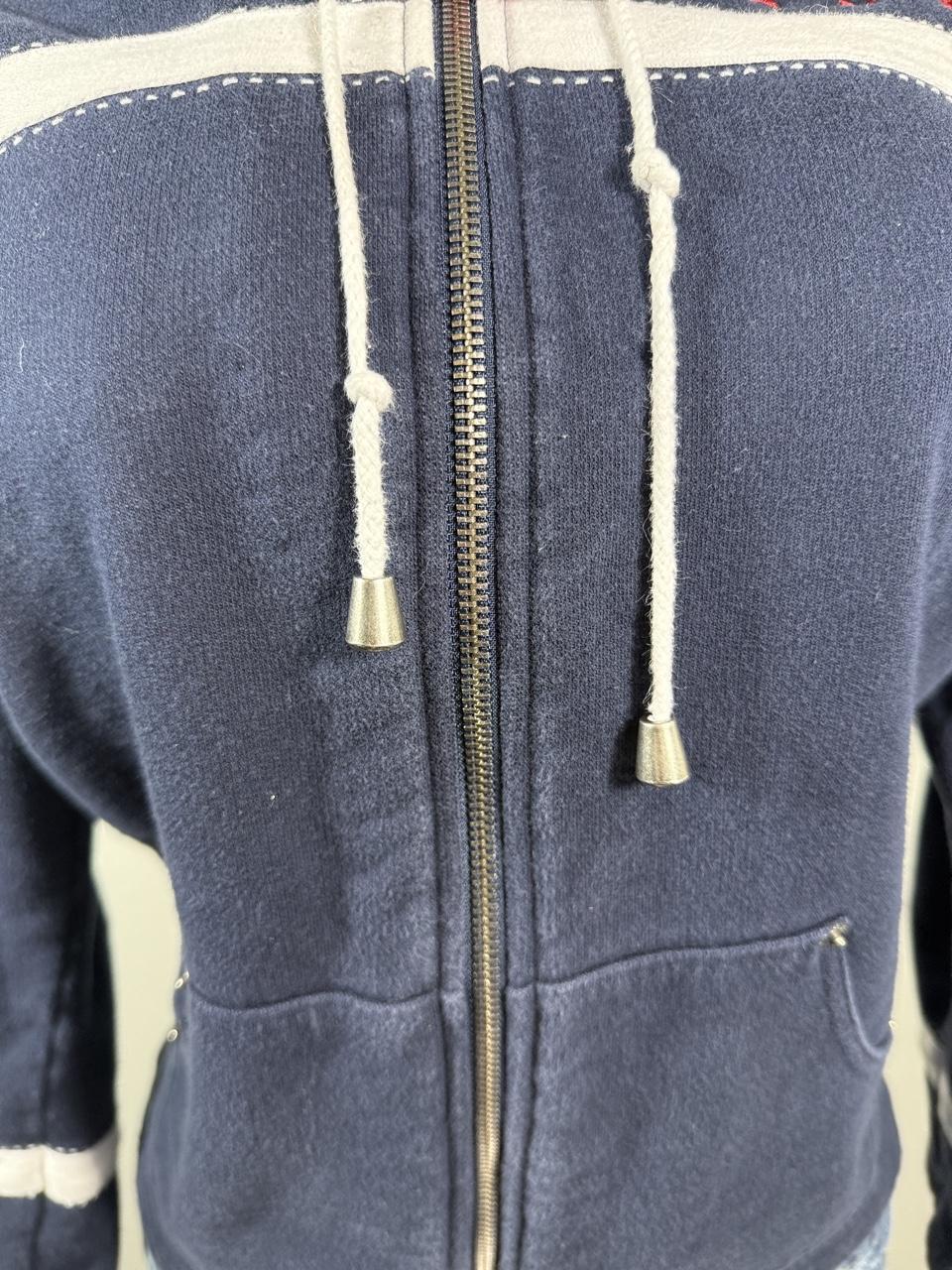 Y2K Studio Norton navy zip-up hoodie featuring sporty white stripe details, red embroidered stars, and a cozy hood with adjustable drawstrings. A classic early 2000s layering piece that's perfect with jeans, cargos, or athleisure looks.