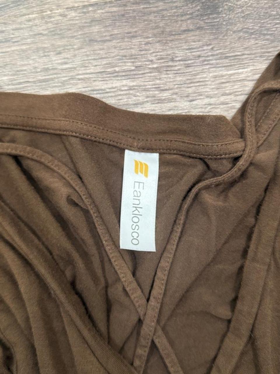 Y2K brown criss cross V-neck tee featuring a flattering fitted silhouette and soft stretchy fabric. A versatile everyday essential that's perfect for pairing with low-rise jeans, cargos, or layering for an effortless early 2000s look.