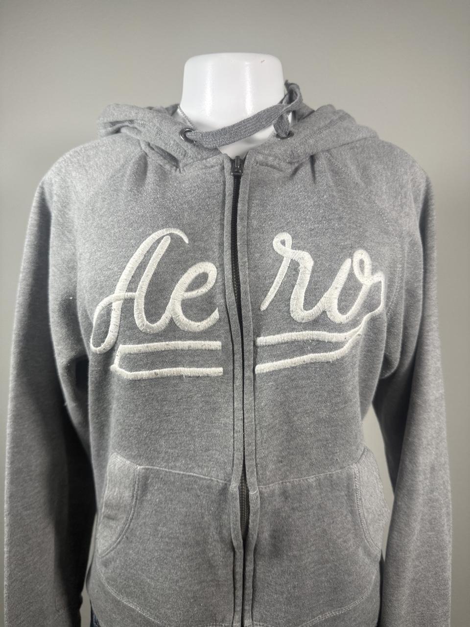 Y2K Aeropostale gray full zip hoodie featuring a large embroidered Aero script logo across the front, soft fleece lining, adjustable drawstring hood, and front kangaroo pockets. The perfect casual layering piece with an authentic early 2000s look.
