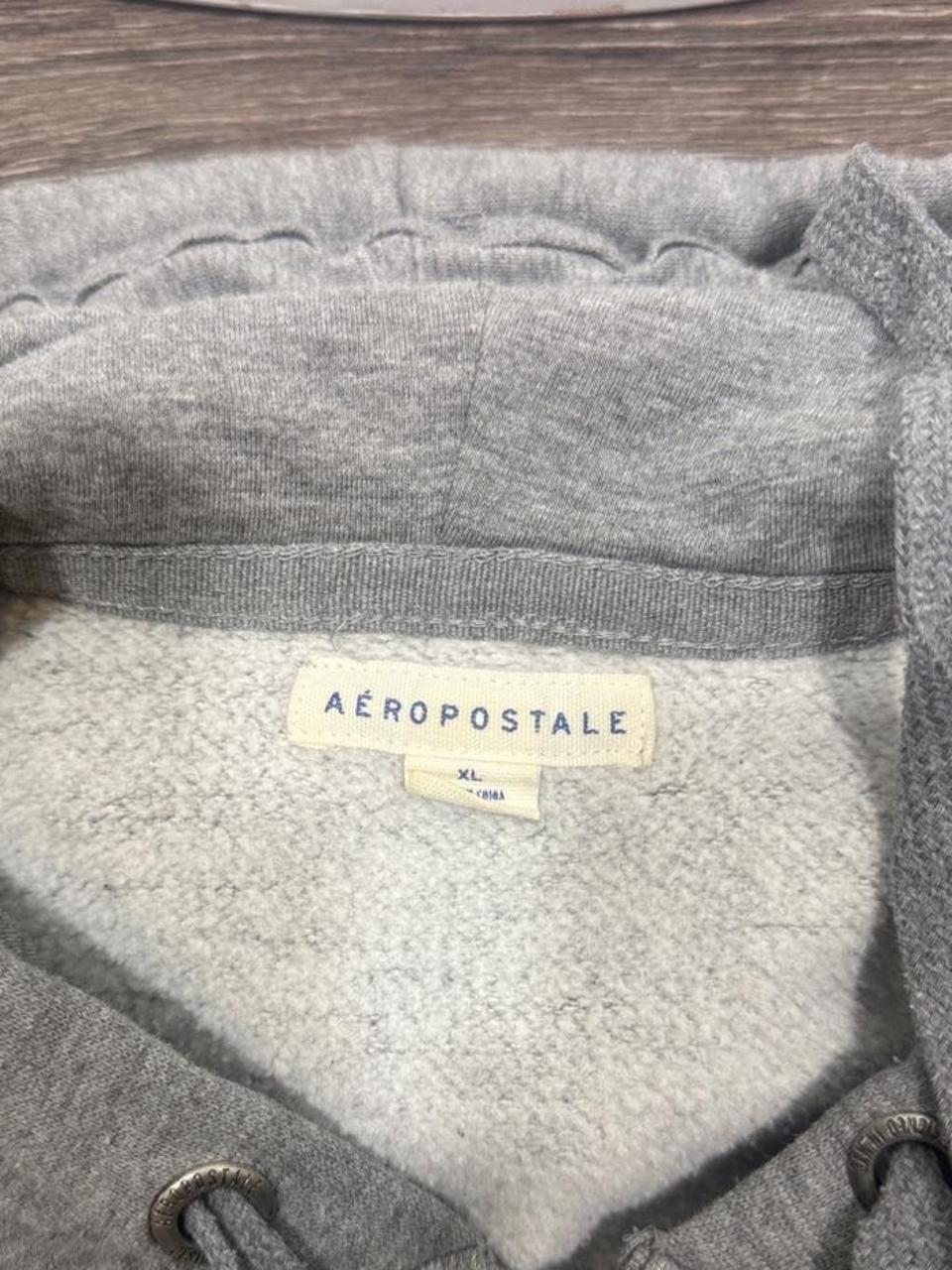 Y2K Aeropostale gray full zip hoodie featuring a large embroidered Aero script logo across the front, soft fleece lining, adjustable drawstring hood, and front kangaroo pockets. The perfect casual layering piece with an authentic early 2000s look.