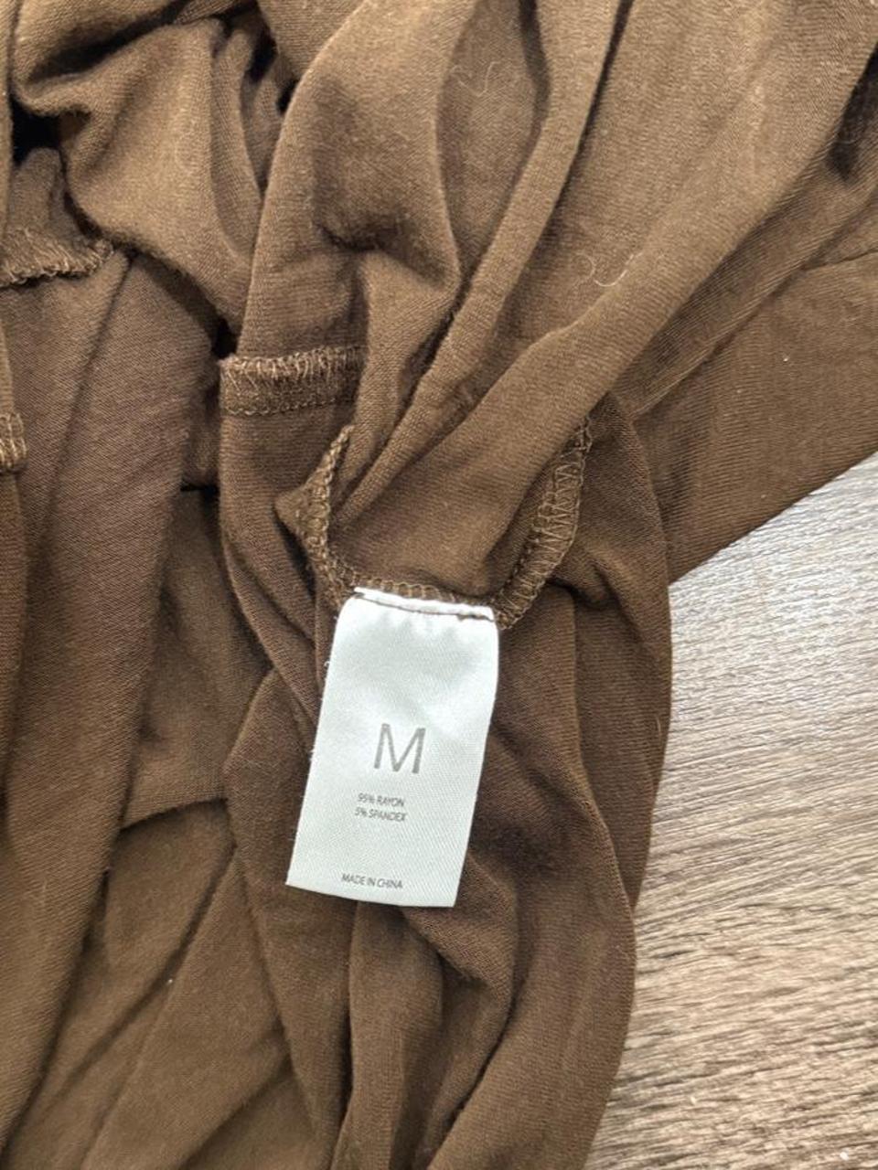 Y2K brown criss cross V-neck tee featuring a flattering fitted silhouette and soft stretchy fabric. A versatile everyday essential that's perfect for pairing with low-rise jeans, cargos, or layering for an effortless early 2000s look.